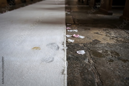 Close up of a white fabric wedding aisle runner on a chapel floor with a shoe smudge