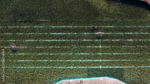 Top down aerial view of people swimming in the ocean pool.