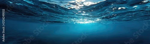 Obraz  z motywem Underwater view, sun rays filtering through ocean waves, creating a tranquil deep blue scene
