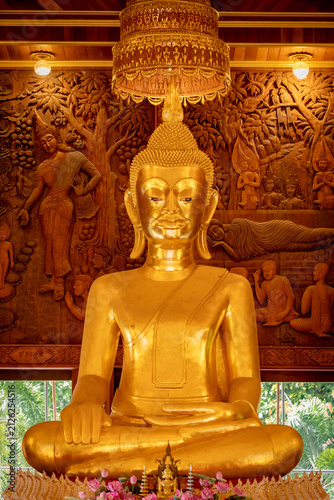 Fotografie Golden Buddha statue with carved wood relief background in Thai temple