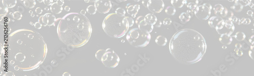 Transparent soap bubbles reflecting colorful light floating against a black background on transparent background