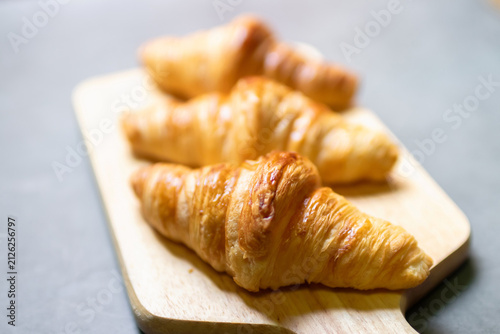 Принти на полотні Fresh baked croissant flaky butter pastry golden brown arranged on wooden board