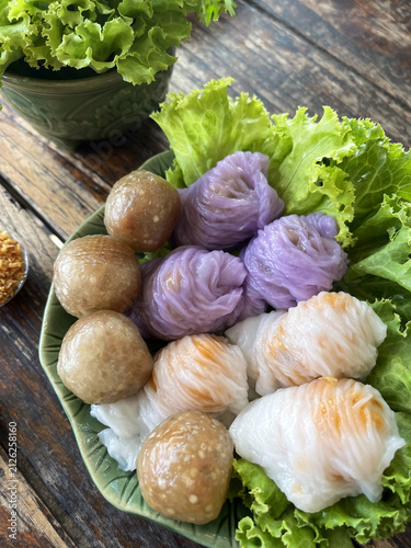 Foto Purple dumpling rice noodle wrap on lettuce with sticky rice balls and wooden ta
