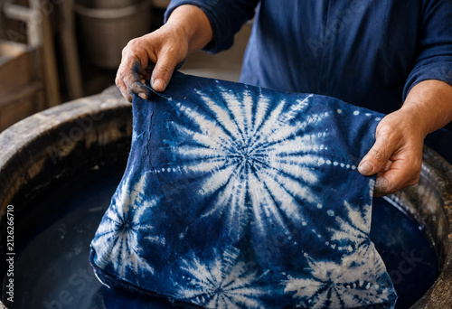 Artisan holding hand-dyed indigo shibori fabric with starburst pattern