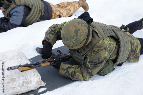 Canvastavla Ukrainian soldier in military uniform lying in snow reloading Kalashnikov assaul