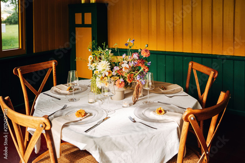 Festively Decorated Dining Table with Fresh Floral Arrangement, Elegant Event Setup in Soft Natural Daylight