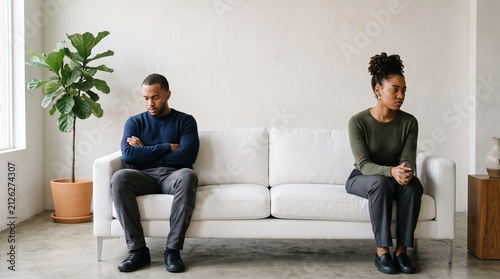 A couple sits on opposite ends of a couch, physically distanced and emotionally estranged, a visual representation of relationship breakdown and emotional disconnect.
