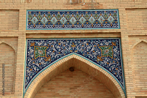 Tile decorations situated above the window of a structure in Uzbekistan. The tiles feature floral and geometric motifs.