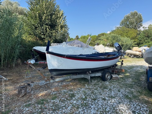 Canvastavla Classic small fishing boat on trailer parked in outdoor boatyard with trees under blue sky