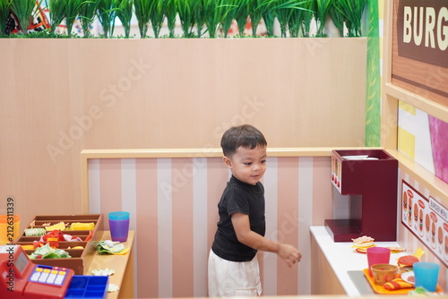Konstfotografi Asian boy playing roleplay game at pretend fast food kitchen in playground