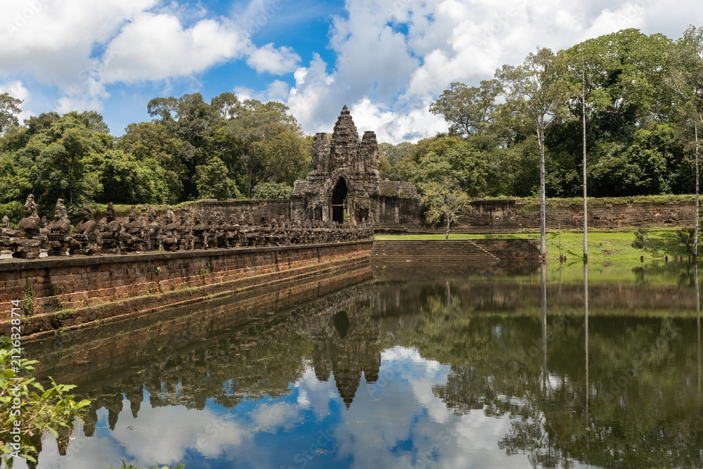 Fototapeta premium South Gate of Angkor Thom with its iconic stone causeway, ancient guardian statues and reflection in the moat, Siem Reap, Cambodia