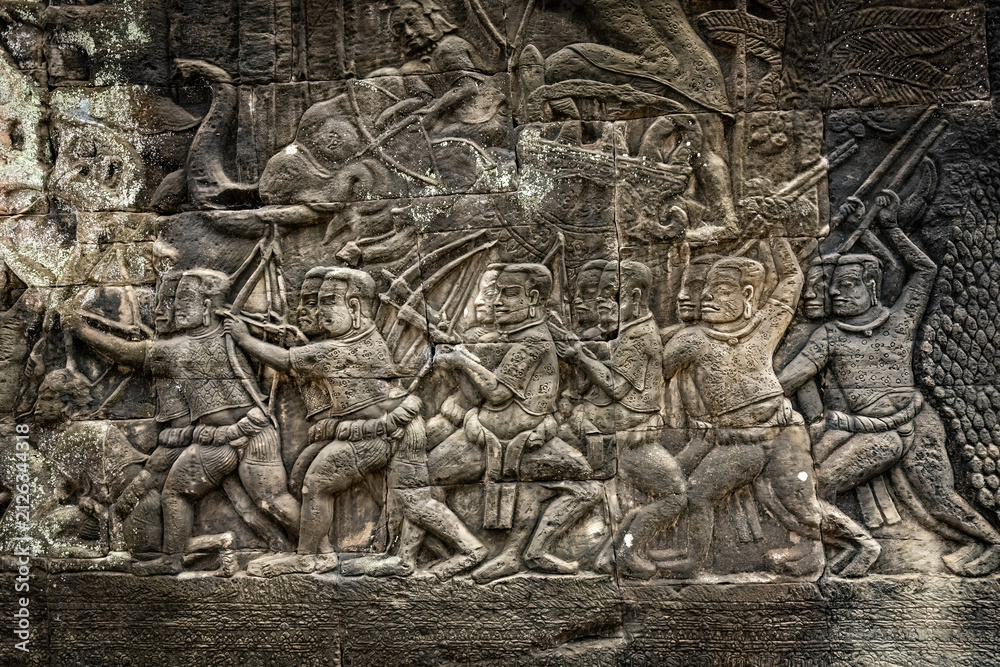 Fototapeta premium Ancient sandstone bas-relief depicting a historical battle and warriors on the walls of Bayon Temple in Angkor Thom, Siem Reap, Cambodia