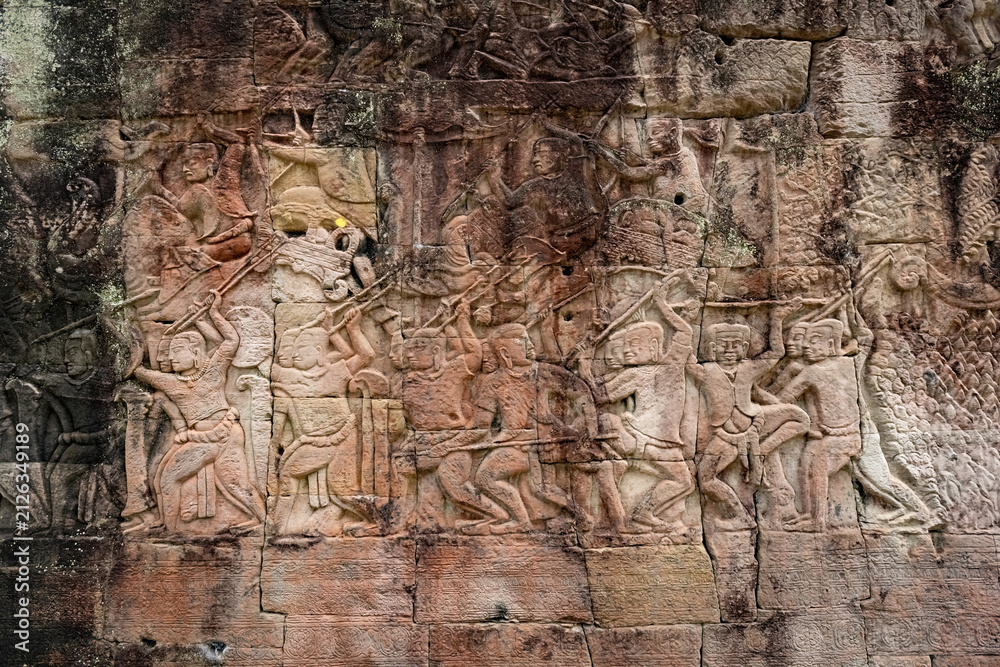 Fototapeta premium Ancient sandstone bas-relief depicting a historical battle and warriors on the walls of Bayon Temple in Angkor Thom, Siem Reap, Cambodia