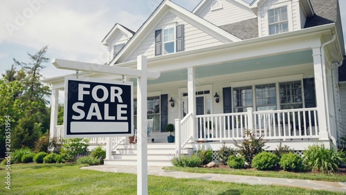 White house with front porch and for sale real estate sign in yard