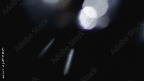 Silver white light reflection and soft blurry spots on a dark grainy background. Simple light streak effect for dark theme photo overlays and posters.