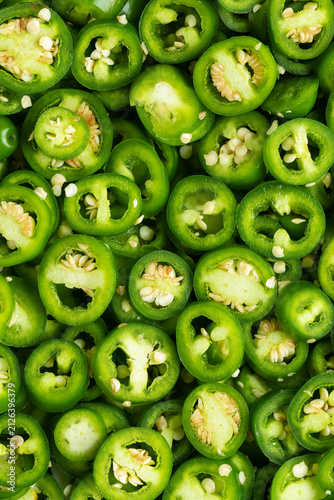 Sliced, green, unripe jalapeño as background texture. Top view of freshly harvested organic chilies from your own garden. Preparing asian-style pickled jalapeño.