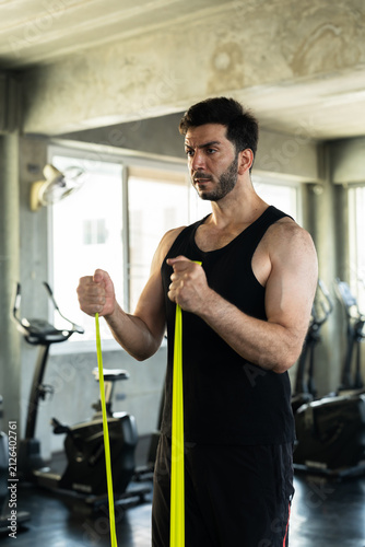 Adult Caucasian man holding green resistance band handles in modern gym, upright stance before bicep curl workout, active male strength routine, fitness motivation, wellness content for gym ads