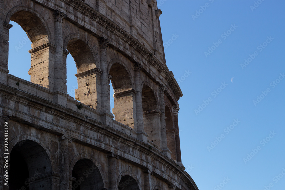 Obraz premium Side View Detail of Roman Colosseum Arches with Crescent Moon in Blue Sky