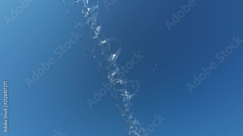 Dynamic Water Stream Splashing Diagonally Across Blue Sky with Birds Flying
