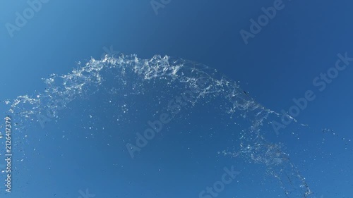 Arc of Water Splashing Upwards Against Clear Blue Sky in Slow Motion