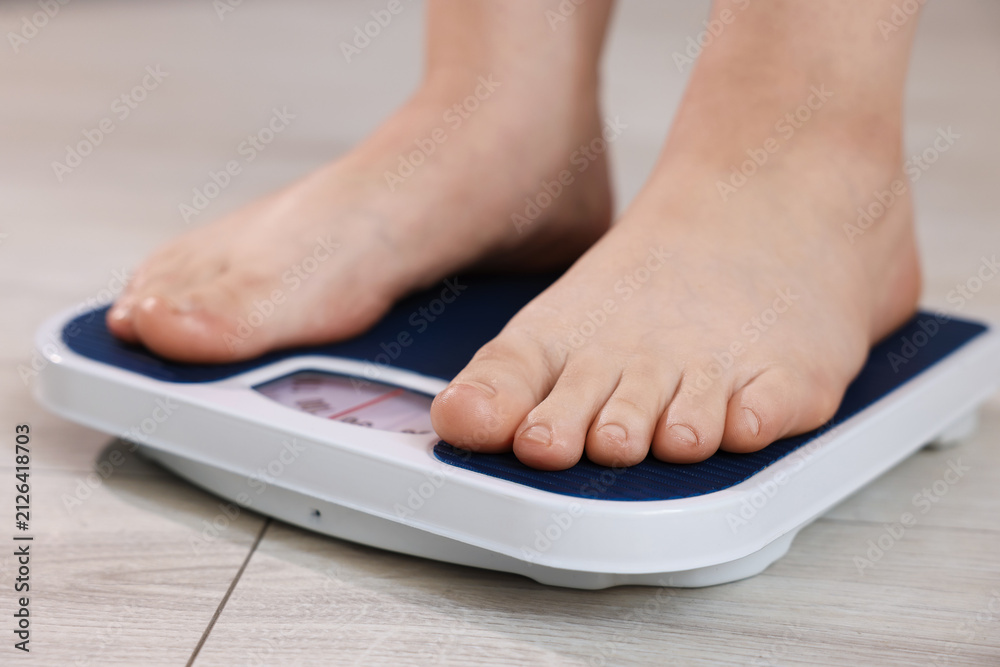 Fototapeta premium Overweight woman on scale at home, closeup