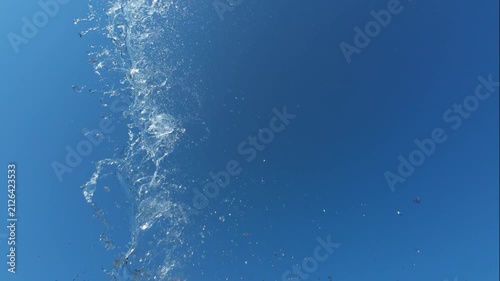 Clear Water Stream Flowing Vertically Against Sunlit Blue Sky