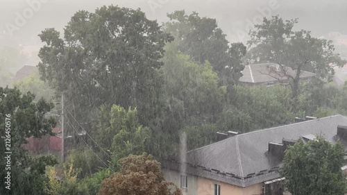Heavy Torrential Rain and Storm Over Houses and Green Trees