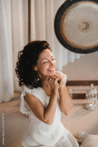 Fotografie Woman in white clothes with closed eyes sitting in a fitness class