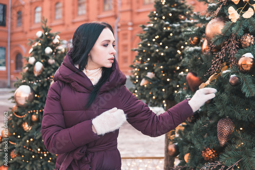 Canvas Print Woman touching Christmas tree decoration on snowy Moscow street