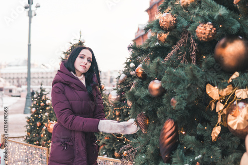 Photography Woman touching Christmas tree decoration on snowy Moscow street