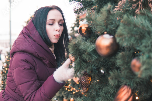 Photography Woman touching Christmas tree decoration on snowy Moscow street