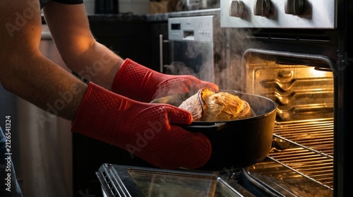 Pulling sourdough bread out of a hot oven showing steam rising from the crust