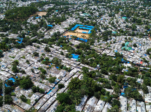 Fotografie Aerial view of the dense Rohingya refugee camp with makeshift shelters and metallic roofs nestled among trees in Cox's Bazar, Chittagong Division, Bangladesh