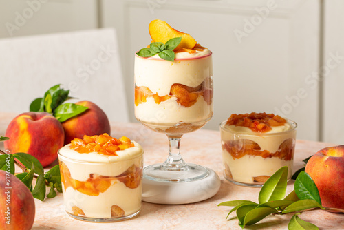 Peach tiramisu in glass cups with mascarpone cream and fresh peaches.
