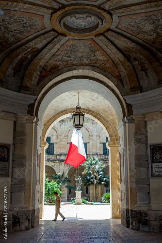 Bild auf Leinwand Frescoed archway frames the Auberge de Castille courtyard, Malta, with a flag ha