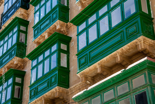 Rows of enclosed green wooden balconies line a stone facade in a striking architectural pattern, Valletta, Malta