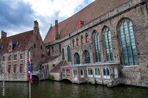 Bild auf Leinwand Historic brick buildings rising directly above a picturesque canal in Bruges, Be