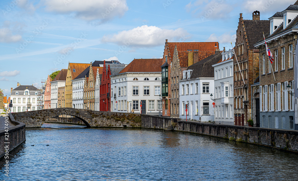 Obraz premium Picturesque canal with stone bridge and colorful historic houses in Bruges, Belgium highlighting authentic Flemish architecture and preserved medieval urban landscape
