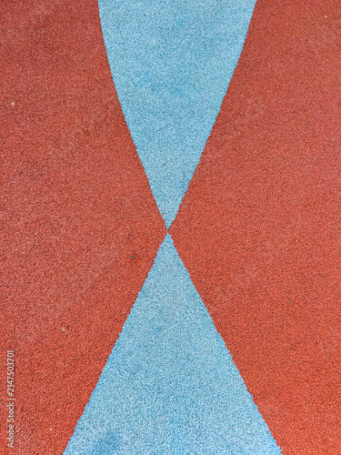 Colorful surface showing blue and red patterns on a playground area in the afternoon sun