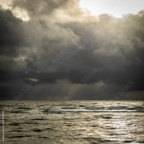 Dramatic sunrise over the ocean with stormy clouds on the horizon