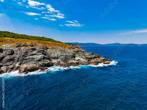 Photography Coastline with rocky cliffs and clear water under blue sky in summer