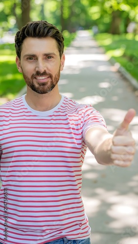 Happy man in striped shirt outdoors smiling warmly.