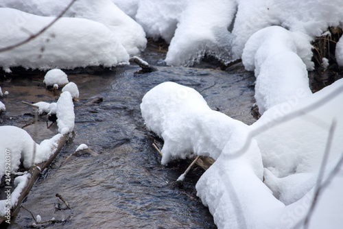 Winter Stream Flowing Through Snow-Covered Logs and Rocks