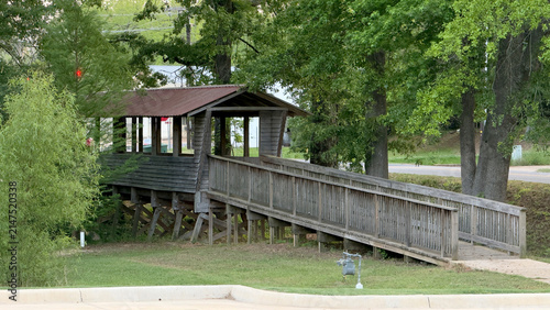 Echoes of the Timber Walk - A rustic wooden pedestrian bridge with an elevated, covered observation deck structures a pathway through lush green summer trees.