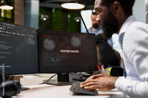 фотографія System administrator types on a keyboard to stop a hacker intrusion in an office, responding to a network attack and working to repair the resulting system breach while protecting company systems