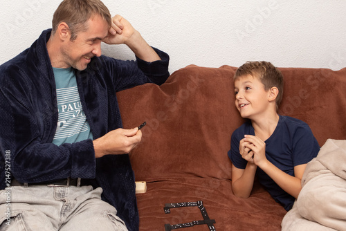Father and son play dominoes at home in the evening while enjoying a family game night