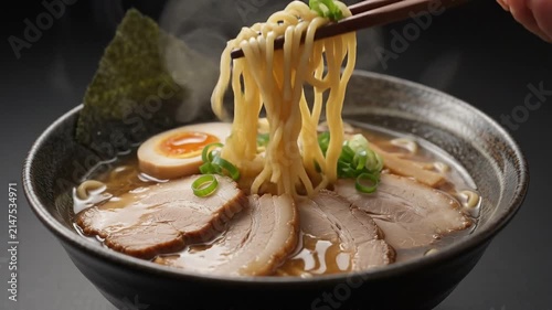 Hot Steaming Japanese Ramen Bowl with Chashu Pork and Egg, Lifting Noodles with Chopsticks, Isolated on Solid Dark Background