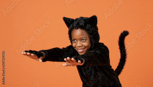 Young child in black cat costume pretending to pounce