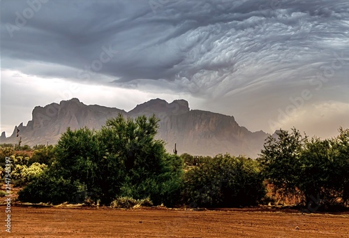 Powerful summer monsoon storm approaching the Superstition Mountains near Phoenix, Arizona, with dramatic swirling storm clouds, blowing rain and rugged desert scenery.