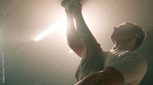 Man reaching upwards against bright light abstract visual composition
